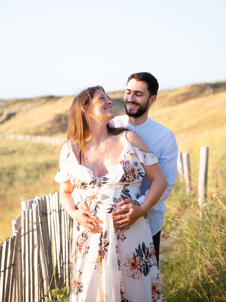 un couple de futurs parents pendant la séance photos grossesse à la plage des sables blancs au conquet