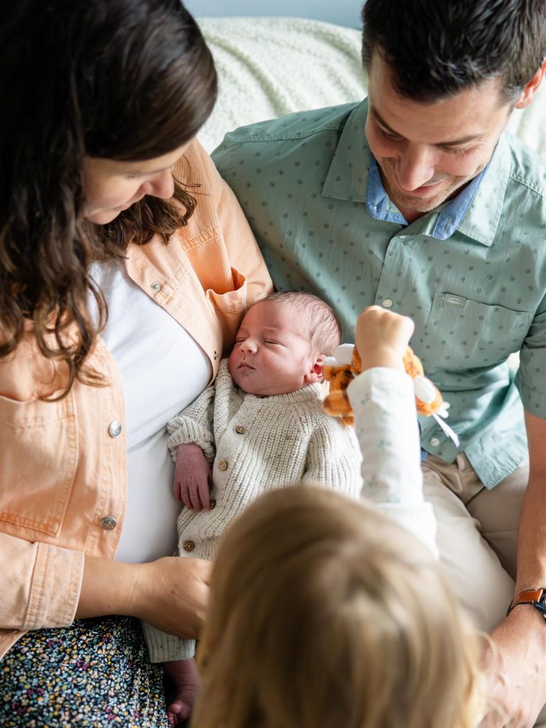 un bébé entouré de ses parents et sa grande soeur pendant la seance photo naissance a la maison a la plouneventer